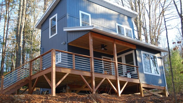 A two-story wooden cabin with a balcony, surrounded by trees. - Charming Cottage Near Downtown, Parkway, and Biltmore (Asheville)