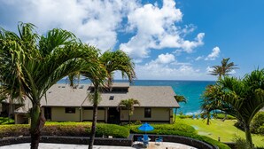 A resort with a pool, palm trees, and a view of the ocean. - Remodeled Family-Size Condo with Fantastic View of the Ocean and Pool (Koloa)