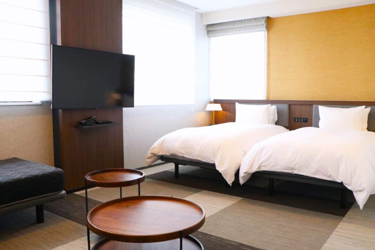 A hotel room with a bed, a TV, a desk, and a chair.
