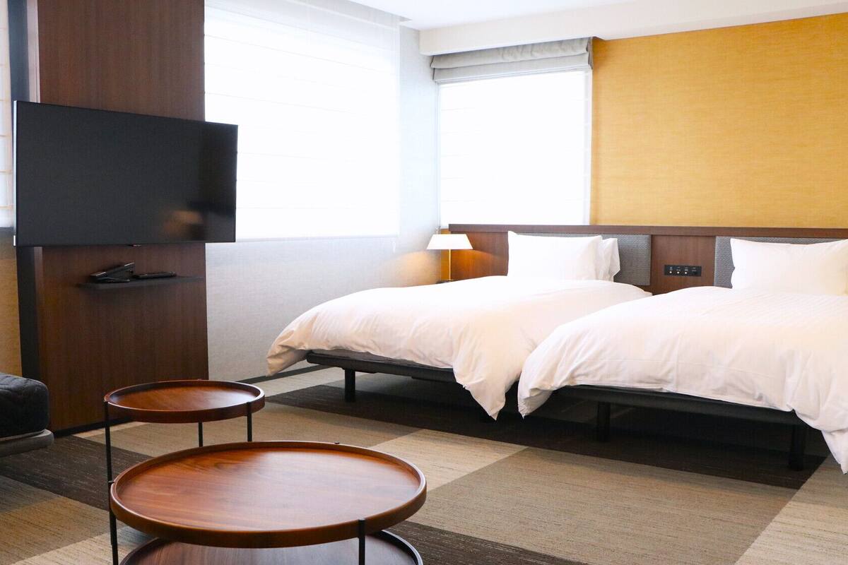 A hotel room with a bed, a TV, a desk, and a chair.