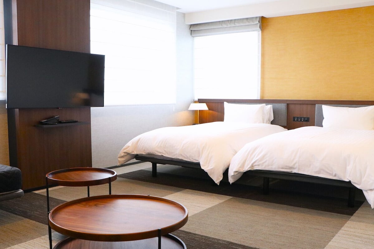 A hotel room with a bed, a TV, a desk, and a chair.