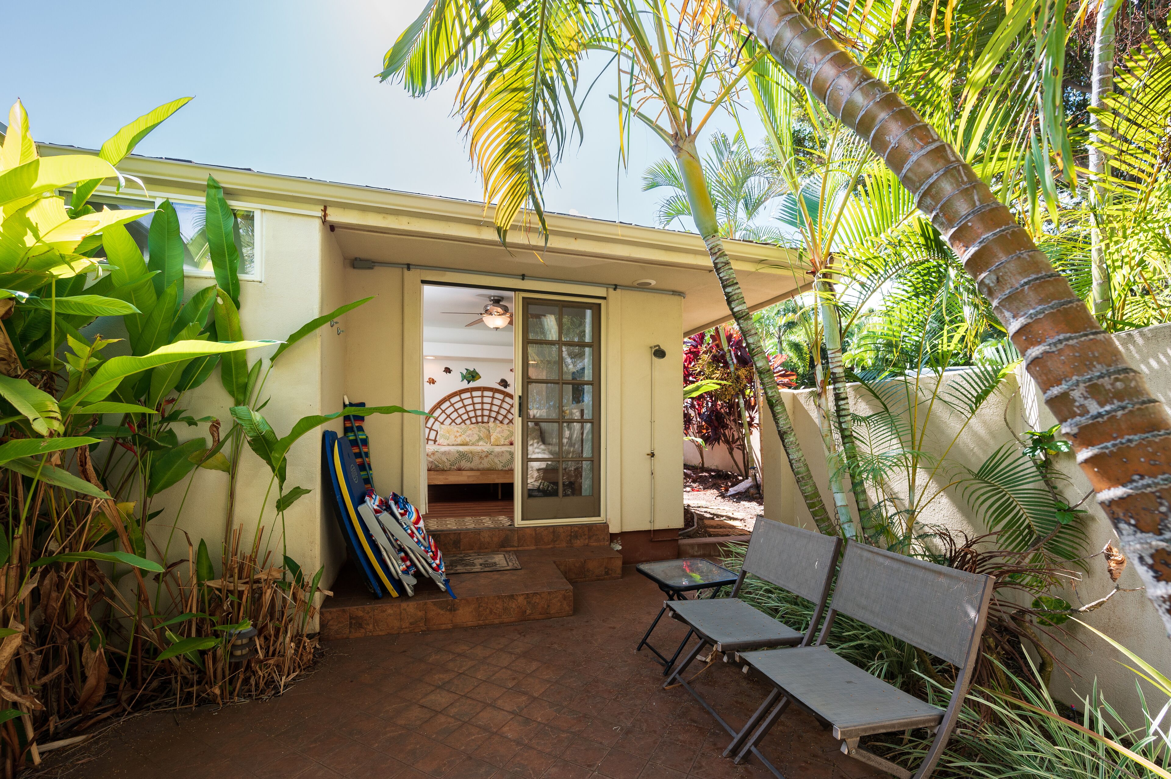 A small house with a patio, a bed, and a door leading to a covered area.