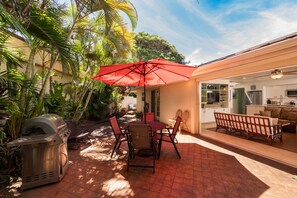 An outdoor patio with a grill, dining table, chairs, and a red umbrella. - 🏝 Private Home, Large Lanai -2 Minute Walk to Poipu Beach! 🐠 (Koloa)