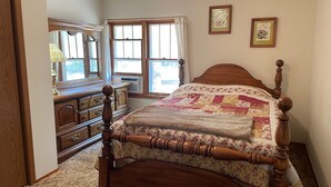 A bedroom with a wooden bed, a dresser, and a window with curtains. - Unplug and enjoy outdoor living at the Lazy Easy (Pet-friendly!) (Bassett)