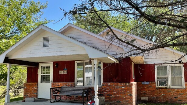 A two-story house with a red brick exterior, a white porch, and a bench. - Unplug and enjoy outdoor living at the Lazy Easy (Pet-friendly!) (Bassett)