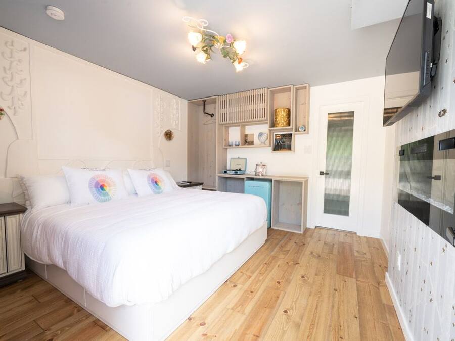 A bedroom with a large bed, a desk, and a TV.