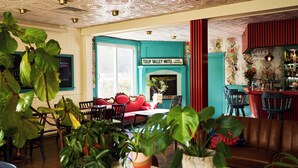 A cozy interior with a teal accent wall, a fireplace, and a bar area. - Motel Chelsea (Chelsea)
