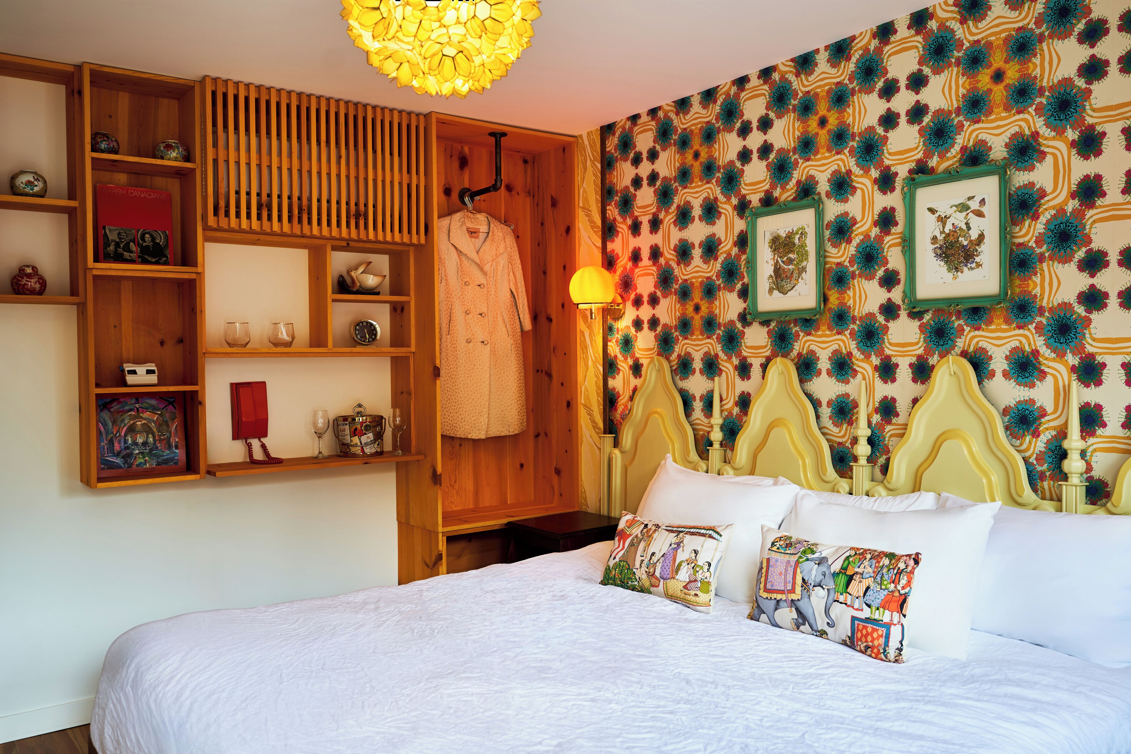 Un dormitorio con una cama grande, estanterías de madera, un armario y un papel tapiz estampado.