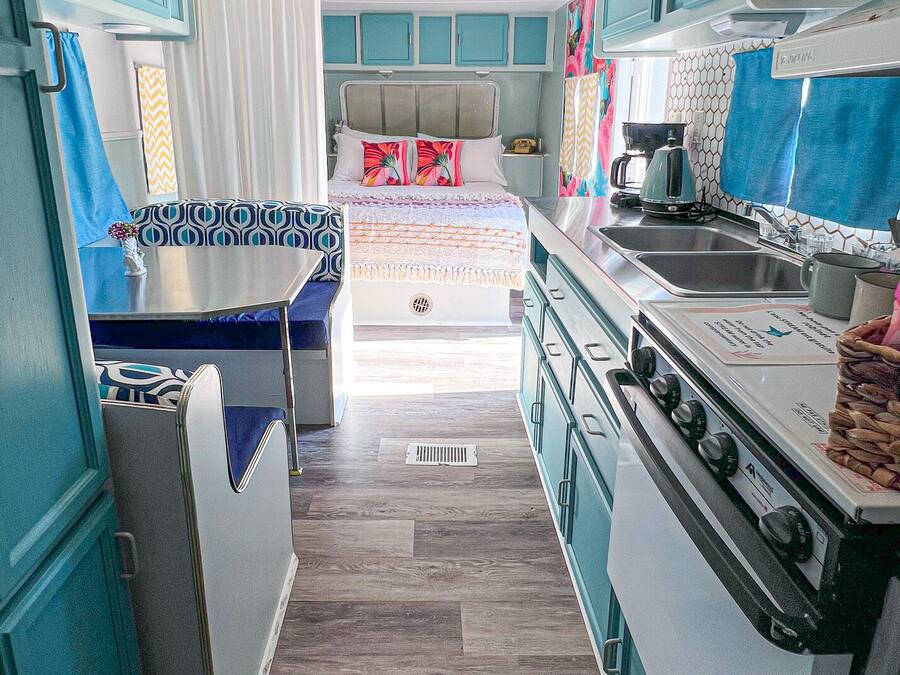 Cocina compacta con estufa, pileta y una cama con cabecera.