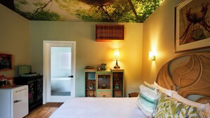 A bedroom with a bed, a dresser, a lamp, and a door. - Motel Chelsea (Chelsea)