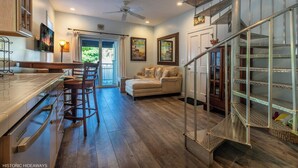 A spacious kitchen with a bar area, a dining set, and a staircase leading to a loft. - Campbell Suite (Key West)