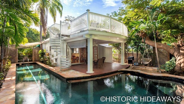A poolside area with a covered seating area, a spiral staircase, and a pool. - Poinciana House (Key West)