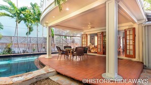 A covered outdoor patio with a pool, wicker furniture, and a view of the backyard. - Poinciana House (Key West)