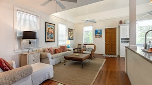 A spacious living room with a sofa, armchair, and coffee table, a dining area with a table and chairs, and a kitchen with a countertop and cabinets. - Quilted Giraffe (Key West)