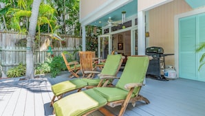 A covered outdoor patio with wooden deck chairs and a grill. - Quilted Giraffe (Key West)