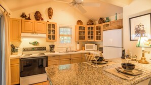 Una cocina con encimeras de granito, armarios de madera, estufa y refrigerador.