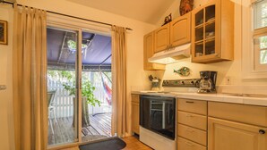 Una cocina con gabinetes de madera, una estufa y una puerta corrediza de vidrio que da a una terraza.