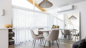 A modern dining area with a round table and four chairs, a large mirror, and a hanging light fixture.