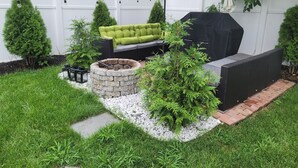 A backyard with a stone fire pit, green outdoor furniture, and a barbecue grill. - Charming 3 bed/2 bath town home with gorgeous back yard (Springfield)
