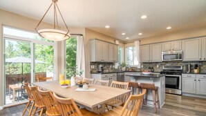A spacious kitchen with a large island, wooden chairs, and a dining table. - Hot Tub + Deck | Walk to Pickleball | Near Central Bend | Canal Trail Base Camp (Bend)