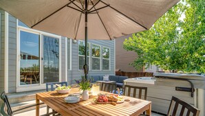 A wooden patio table with a beige umbrella, surrounded by chairs. - Hot Tub + Deck | Walk to Pickleball | Near Central Bend | Canal Trail Base Camp (Bend)