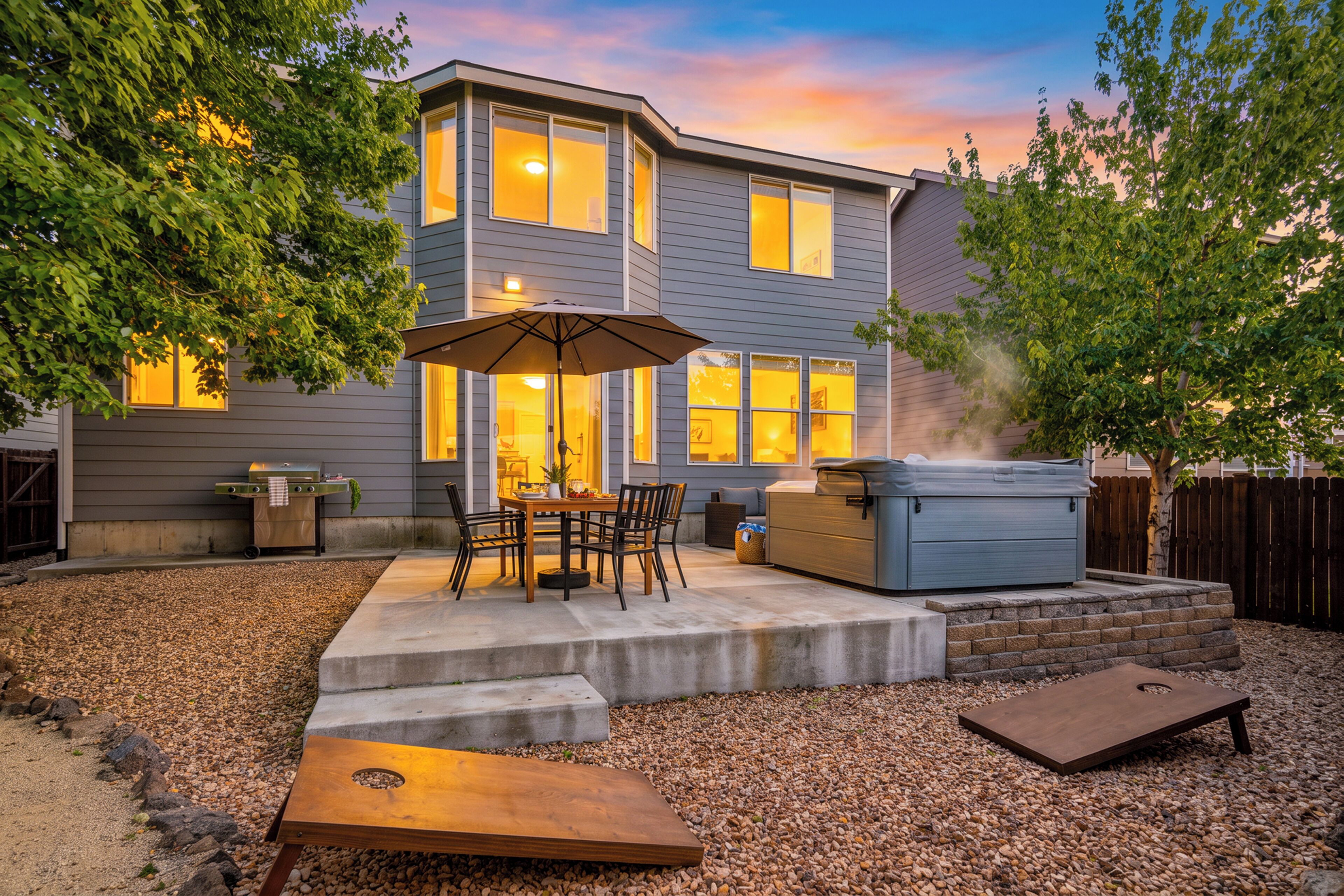 A residential backyard with a patio, outdoor furniture, a hot tub, and a grill.