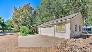 Une maison de plain-pied avec un garage, entourée d’une allée en gravier et d’un petit jardin de rocaille.