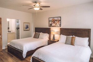 A hotel room with two beds, wooden headboards, a ceiling fan, a framed picture, and a nightstand with a lamp. - Ranch House Interior - 4 bedroom, 4 bath home on-site of Galway Downs (Temecula)