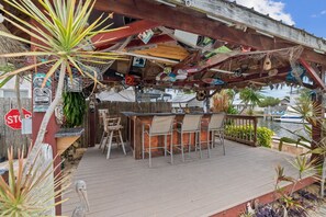 A wooden deck with a bar area, chairs, and a stop sign.