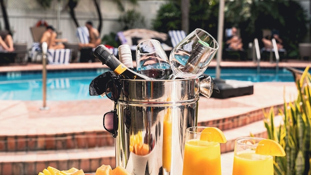 A poolside setting with a fruit bowl, drinks, and sunglasses on a table. - The Grand Resort and Spa  (Fort Lauderdale)