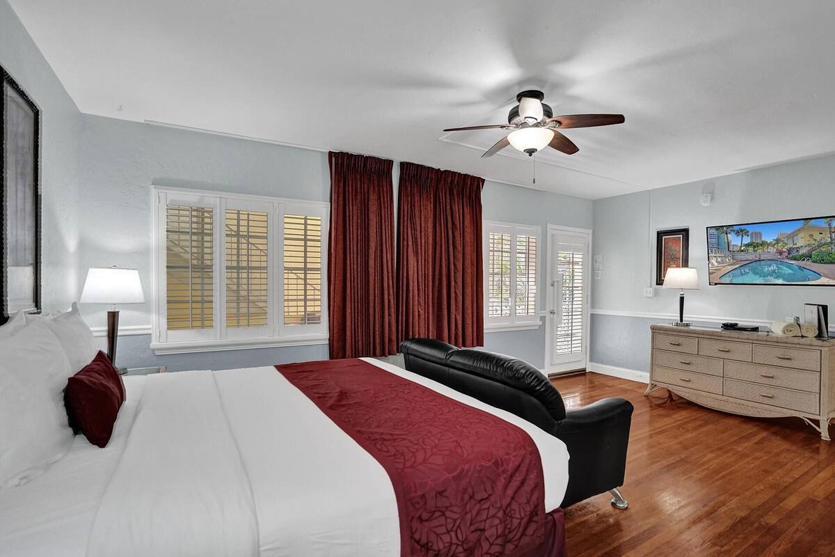 Une chambre d’hôtel équipée d’un lit, d’un bureau, d’une chaise, d’une commode et d’un ventilateur de plafond.