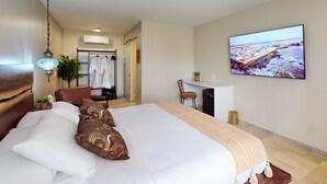 A hotel room with a large bed, a desk, a TV, and a view of a beach. - The Grand Resort and Spa  (Fort Lauderdale)