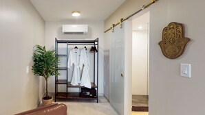 A hallway with a coat rack, a potted plant, and a hand-shaped wall decoration. - The Grand Resort and Spa  (Fort Lauderdale)