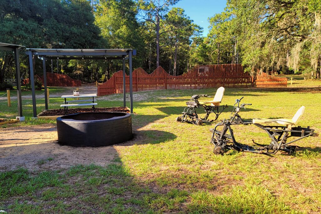 An outdoor area with a covered seating area, a fire pit, and exercise equipment.