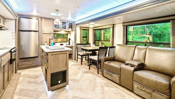 Una cocina moderna para vehículos recreativos, con refrigerador, estufa y comedor.
