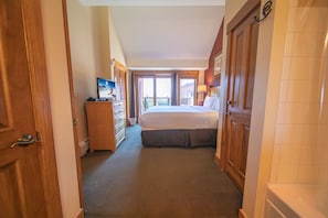 A hotel room with a bed, a desk with a computer, a window with a view, and a door. - Springs 8913 (Keystone)