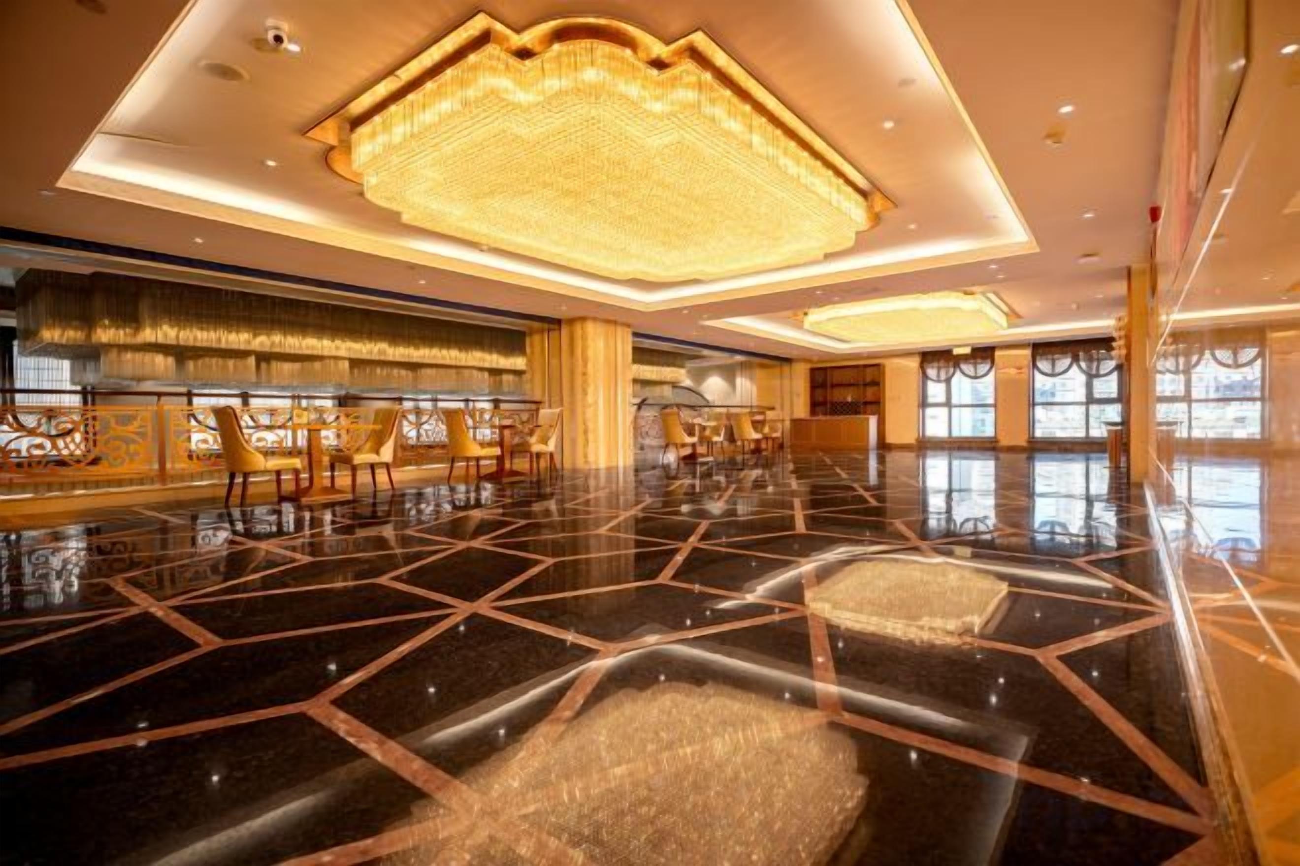 A spacious lobby with a polished floor, a large chandelier, and seating arrangements.