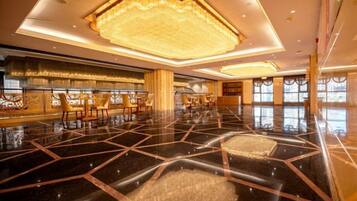 A spacious lobby with a polished floor, a large chandelier, and seating arrangements.