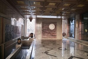 A spacious lobby with a marble floor, a large circular wall feature, and a ceiling with a geometric pattern. - Xingjia Yilong Hotel (Meihekou)