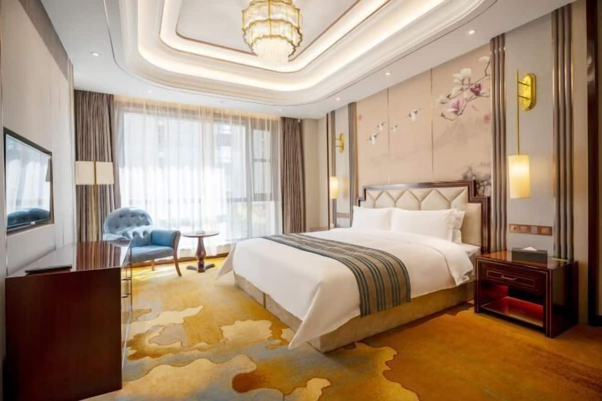 A hotel room with a large bed, a TV, a desk, and a chair.