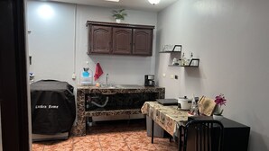 A compact kitchen with a tiled floor, a coffee maker, a kettle, and a table with a tablecloth. - Relax in downtown Alajuela / 5min near the Airport (Alajuela)