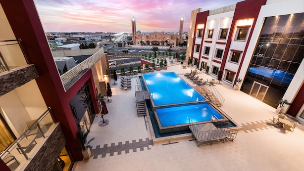 A rooftop pool area with a clear view of the city skyline, including a bridge and a mosque.