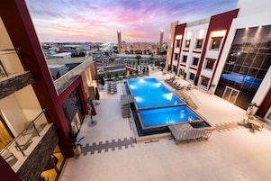 A rooftop pool area with a clear view of the city skyline, including a bridge and a mosque.