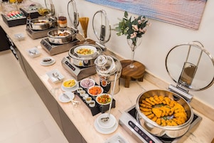 A buffet with various food stations, including a large bowl of orange-colored food, pasta, and other dishes.