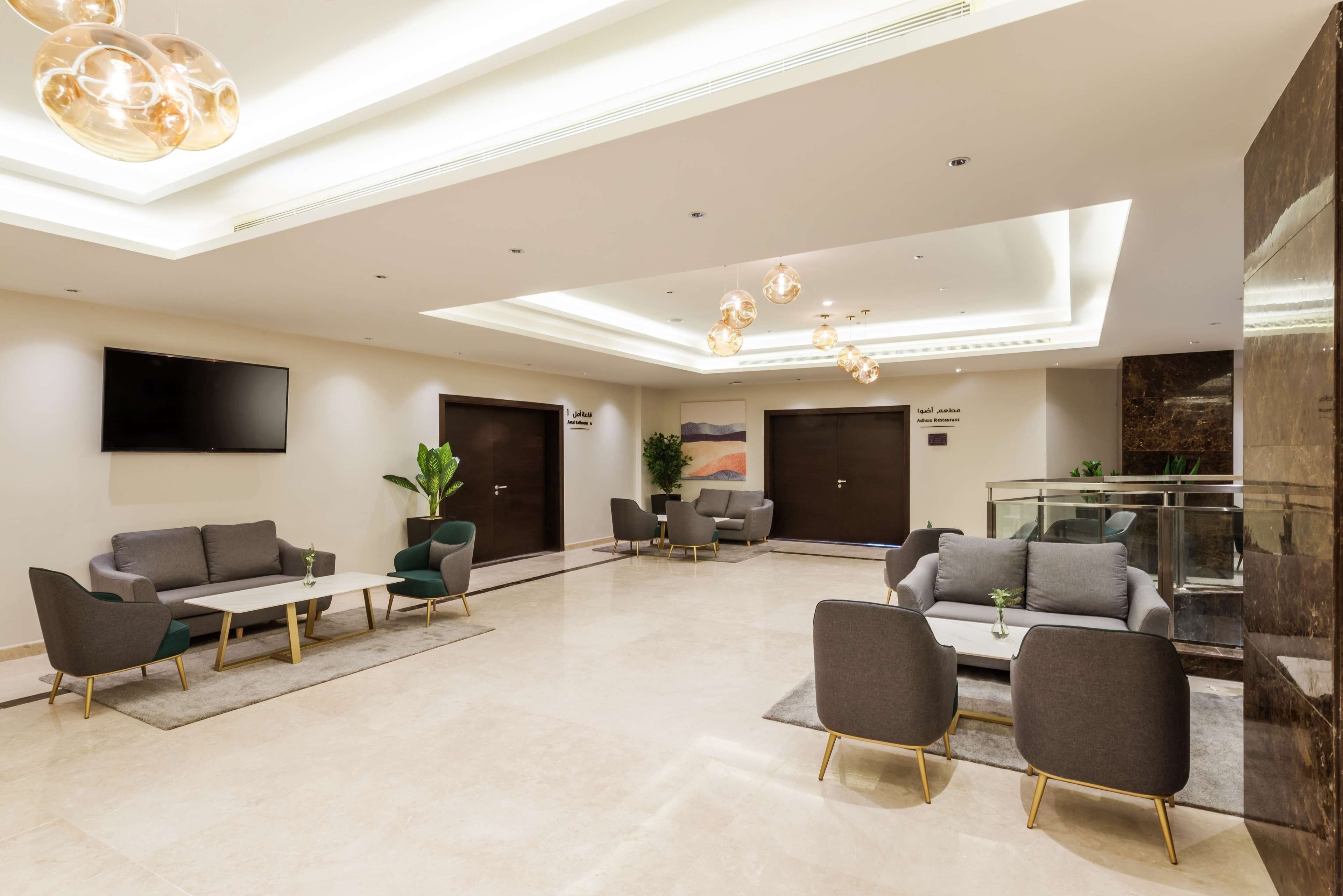 A modern lobby with a seating area, a flat-screen TV, and a glass partition.