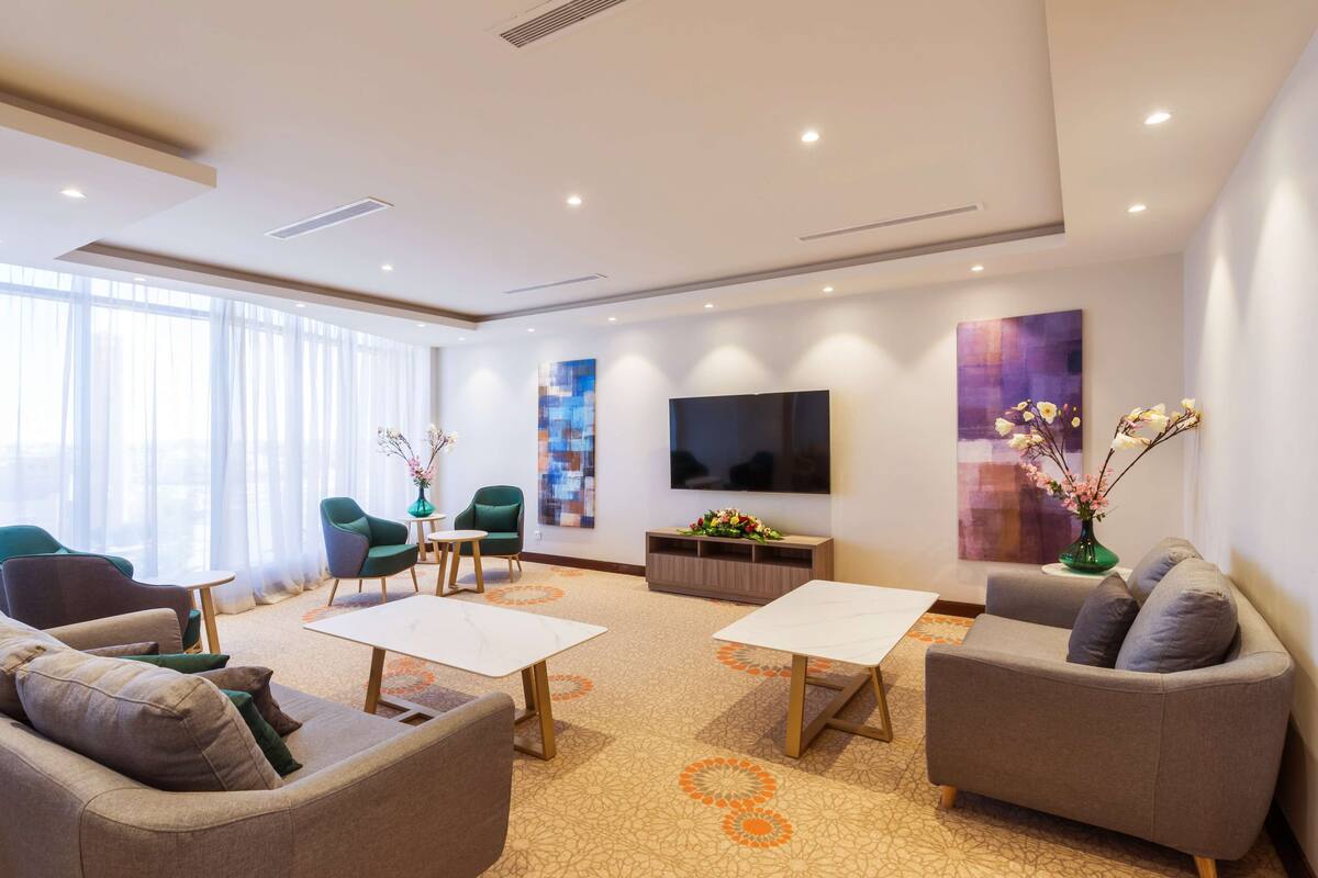 Ein modernes Wohnzimmer mit einer Couch, Sesseln, einem Couchtisch und einem flachbildfernseher an der Wand.