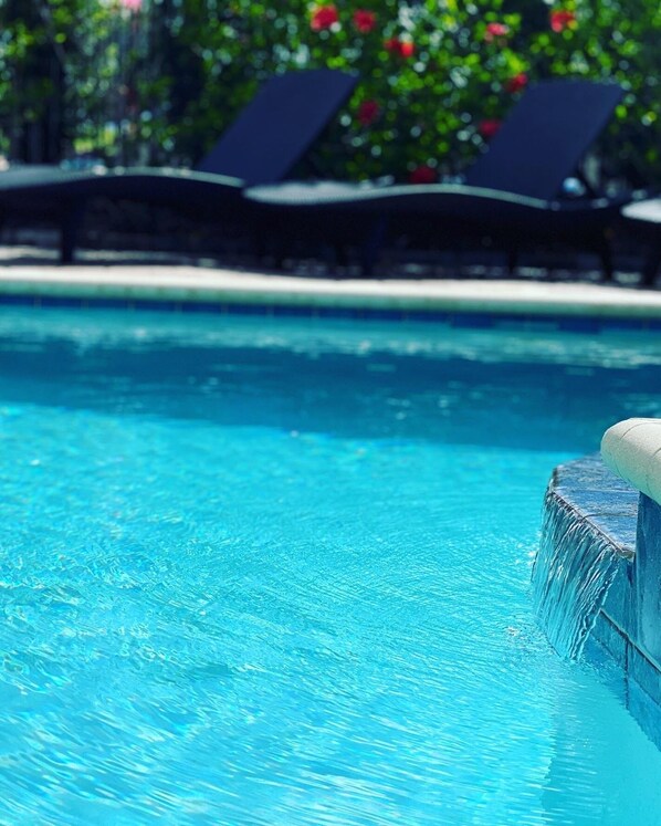 Relax by the inviting pool, surrounded by lush greenery and a soothing waterfall.