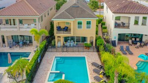 Una casa de dos pisos con piscina, mobiliario exterior y un jardín bien cuidado.
