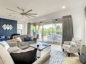 Relax in this stylish living room with a sofa, armchair, and patterned rug, offering a view of the outdoors through the large window.
