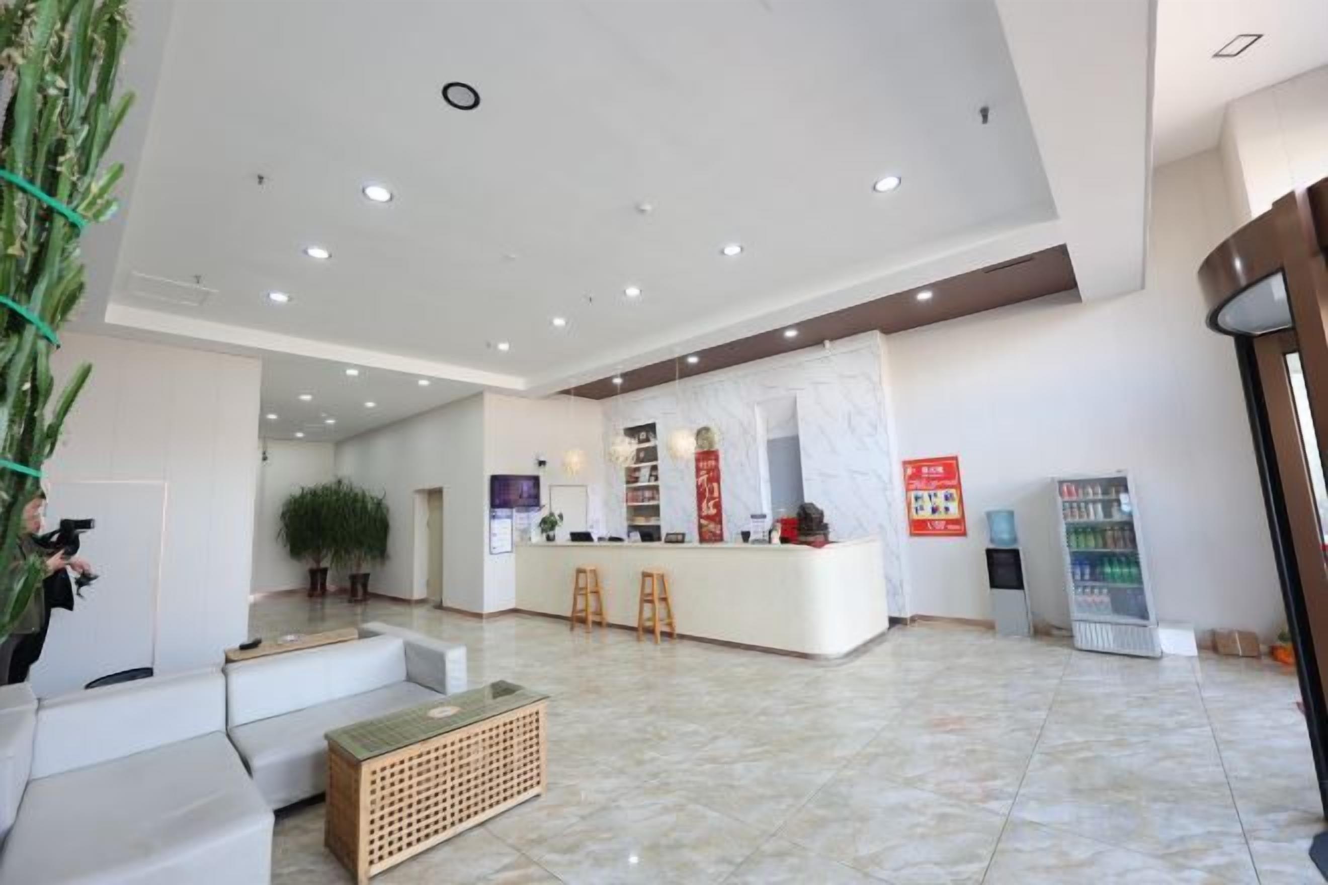 Vestíbulo de hotel con una recepción, zona de estar y una planta.